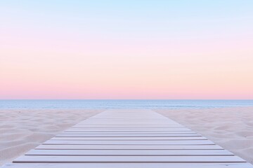Naklejka premium Pastel colored sunset sky painting the horizon above a serene boardwalk stretching toward the ocean, nestled on a sandy beach