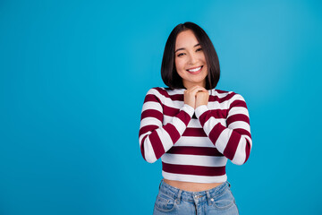 Young woman smiling in casual striped shirt on blue background conveying happiness and charm