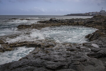 Dramatic coastal scene in Gran Canaria with waves crashing against dark volcanic rocks. El Bufadero
