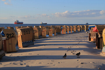 Containerschiffe auf der Kieler Förde am schönen Sandstrand mit Strandkörben am Kurort Laboe an...