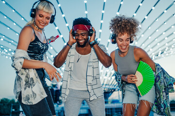 Friends enjoying music festival with wireless headphones