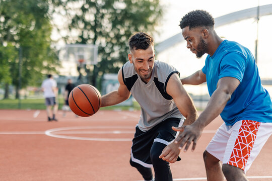 Two male basketball players defending during a match outside