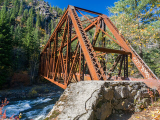 USA, Washington State, Chelan County. Tumwater Canyon Bridge in fall crossing the boulder strewn Wenatchee River. © Danita Delimont