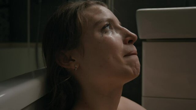 Close-up shot of anxious gen Z girl with smudged mascara and tears on her face suffering from paranoia while hiding in bathroom