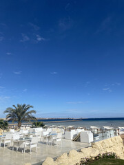 Seaside dining area with white furniture under clear blue sky near the coast