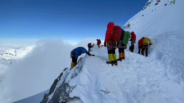 Mountaineers carefully walking on narrow snowy ridge