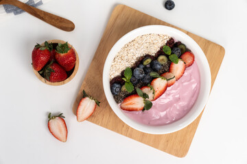 Presented by fruits putting yogurt toppings with strawberry, berry, oats, raisins and chia seed decorated by peppermint in white blow. Pink background. Set of healthy dairy product choice. Pecuniary.