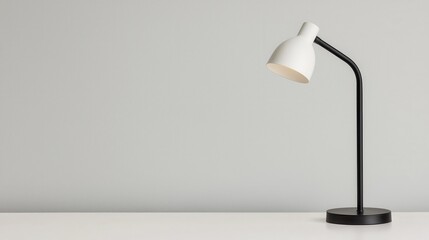 A sleek white desk lamp with a black base sits on a clean, minimalistic surface against a soft gray wall.
