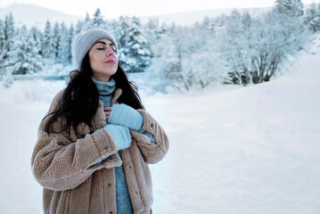 Beautiful woman breathing fresh air in a snowy winter mountain