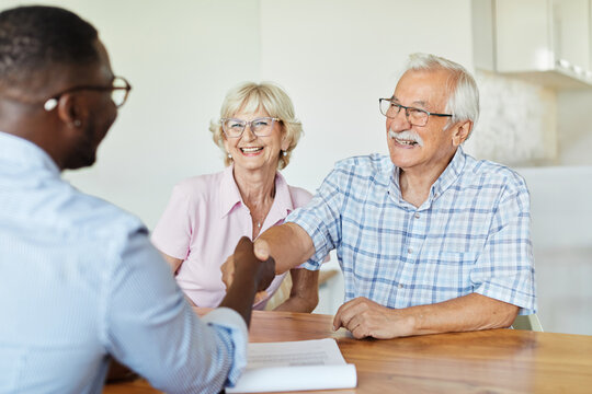man handshake business businessman meeting agreement investment contract deal senior couple retirement house finance insurance planning advice adviser office