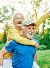 outdoor senior fitness woman man love active fun piggyback exercise healthy fit sport retirement...