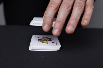 Illusionist with playing cards at black table, closeup