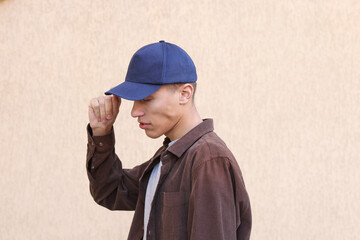 Man in stylish baseball cap near beige wall. Mockup for design