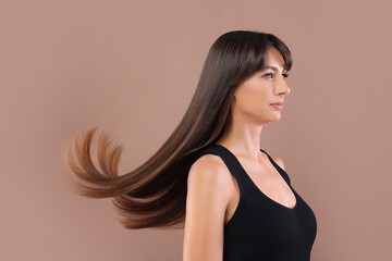 Fototapeta premium Hair styling. Beautiful woman with straight long hair on pale brown background