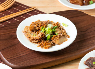Tripe topped with green onion served in plate with fork and chopsticks isolated on wooden board side view of taiwan food