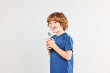 Little boy with microphone on light grey background