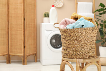 Wicker basket full of laundry on chair in bathroom