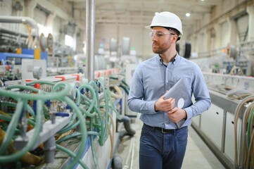 A young male engineer inspects the production of plastic window frames