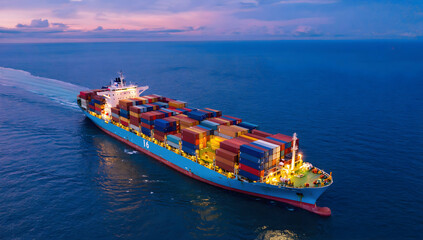 Massive cargo ship sailing at twilight, loaded with colorful containers.