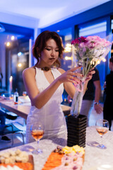Elegantly dressed woman arranging flowers during a social gathering