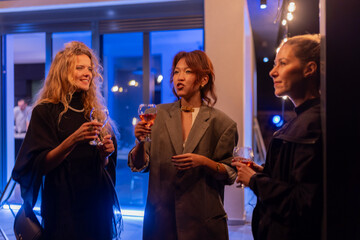 Three friends enjoying wine and conversation at an illuminated evening gathering
