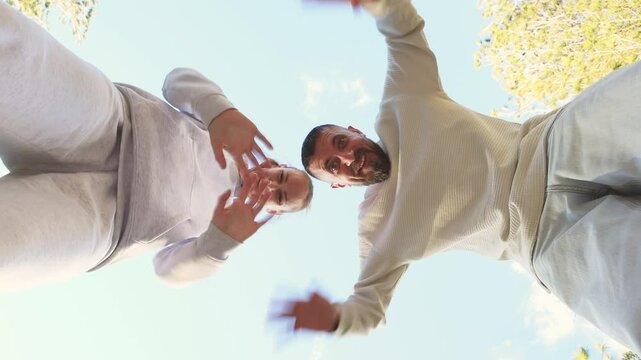 Happy friends jumping, waving arms energetically, celebrating friendship day with pure joy and strong connection, standing against bright sky and green trees. International friendship day