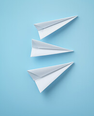Naklejka premium Three white paper airplanes arranged on blue background, showcasing creativity and simplicity