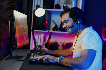 Smart gaming streamer enjoy playing battle team with streaming online shooting gun game with multi or single player at warship on pc screen, wearing headset at digital neon light cyber room. Surmise.