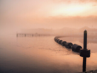 Water dam on River Shannon in Athlone city in a fog at warm sunset. Calm and surreal look. Color of...
