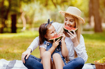 Little Girl And Her Mother Having Sumer Picnic Eating Watermelon Sitting On Plaid In City Park...