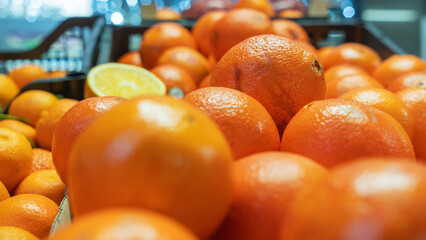 Fresh oranges are beautifully arranged on a bustling market stall, with some fruits in sharp focus...