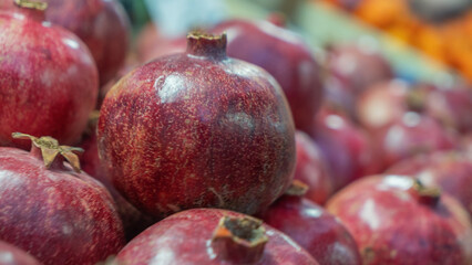A vibrant close-up of a pomegranate at a bustling market, showcasing its rich red color and...