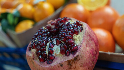 A close-up of a sliced pomegranate showcasing its juicy seeds, set against a softly blurred market...