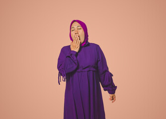 Tired Woman in Purple Hijab Yawning with Hand on Mouth