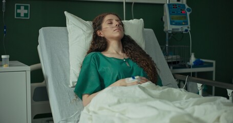 Young African American doctor checks the blood pressure of a young female patient in the hospital room.