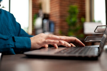 Closeup on hands of startup employee typing on digital device, updating company information at...