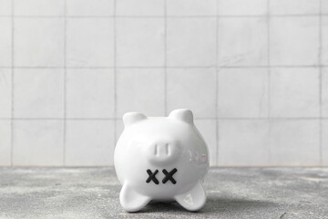 Piggy bank with closed eyes  on grunge table near white tile background. Concept of bankruptcy