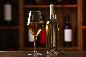 Bottle and glass of exquisite wine on table in cellar