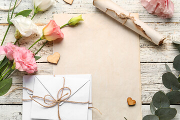 Composition with blank card, envelopes, eucalyptus branch and beautiful eustoma flowers on light wooden background