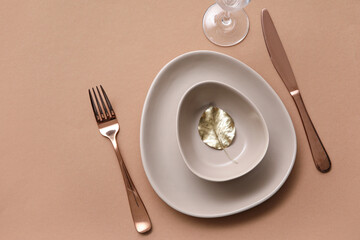 Elegant table setting with golden leaf and cutlery on brown table