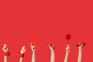 Female hands with different sex toys on red background