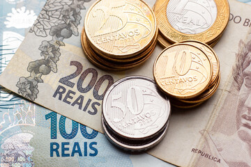 close em nota de 100 e 200 reais com moedas em cima