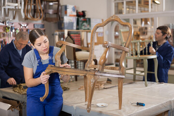 Young female furniture workshop worker designing vintage chair
