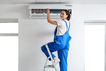 Female technician repairing air conditioner at home