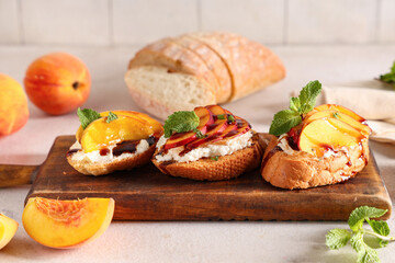 Wooden board of peach bruschetta with ricotta and mint on white table