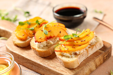 Wooden board of peach bruschetta with ricotta, flax seeds and micro green on beige background