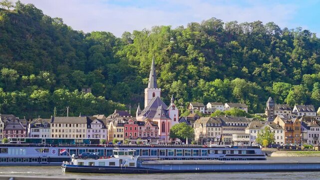 Small town on the banks of the Rhine River with cruise boats and lush hilly landscape on a sunny summer day, St. Goar, Germany