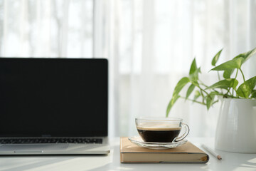 Laptop and coffee cup on a white desk