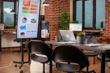 Brick wall room equipped with digital technology for efficient and accurate group presentations. Startup office is well organized for team meetings, prepared with monitors and company documents.