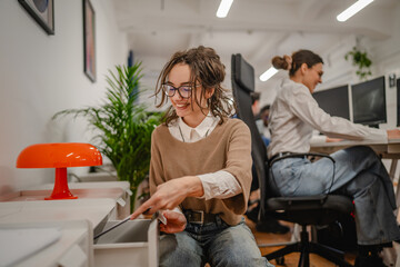 young woman kneel and put clipboard into a drawer in the office